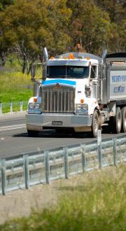 A heavy vehicle driving on a rural road.