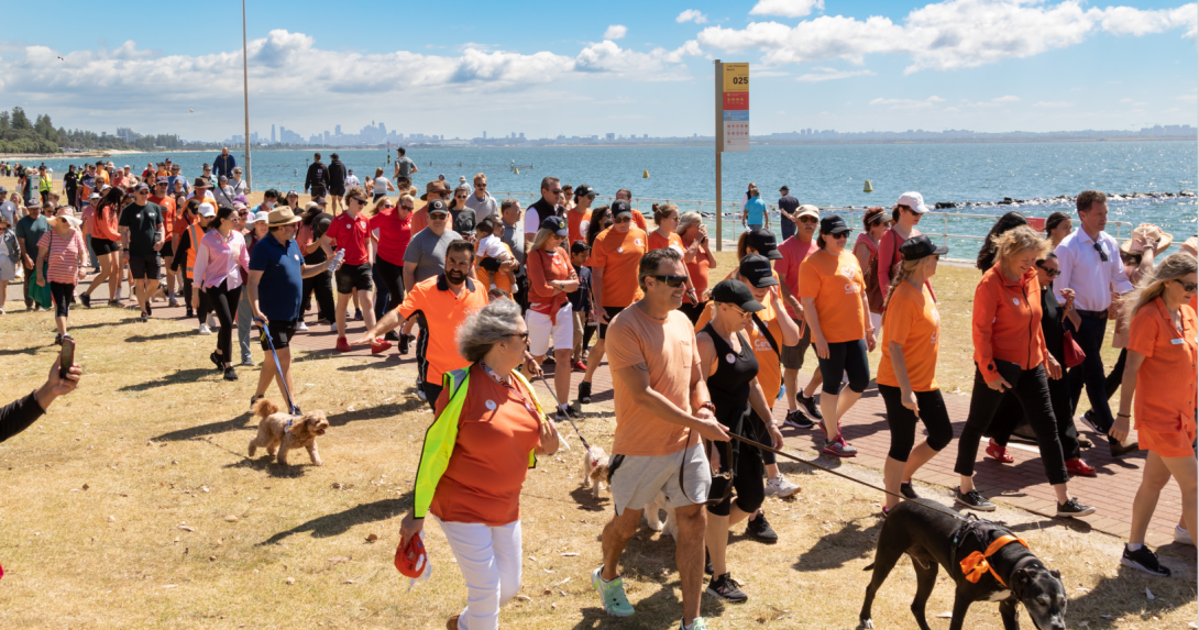Large group of people wearing orange walking on a beach. Photo credit: Bayside Council, NSW
