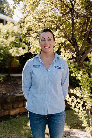 A woman standing in a garden, smiling.