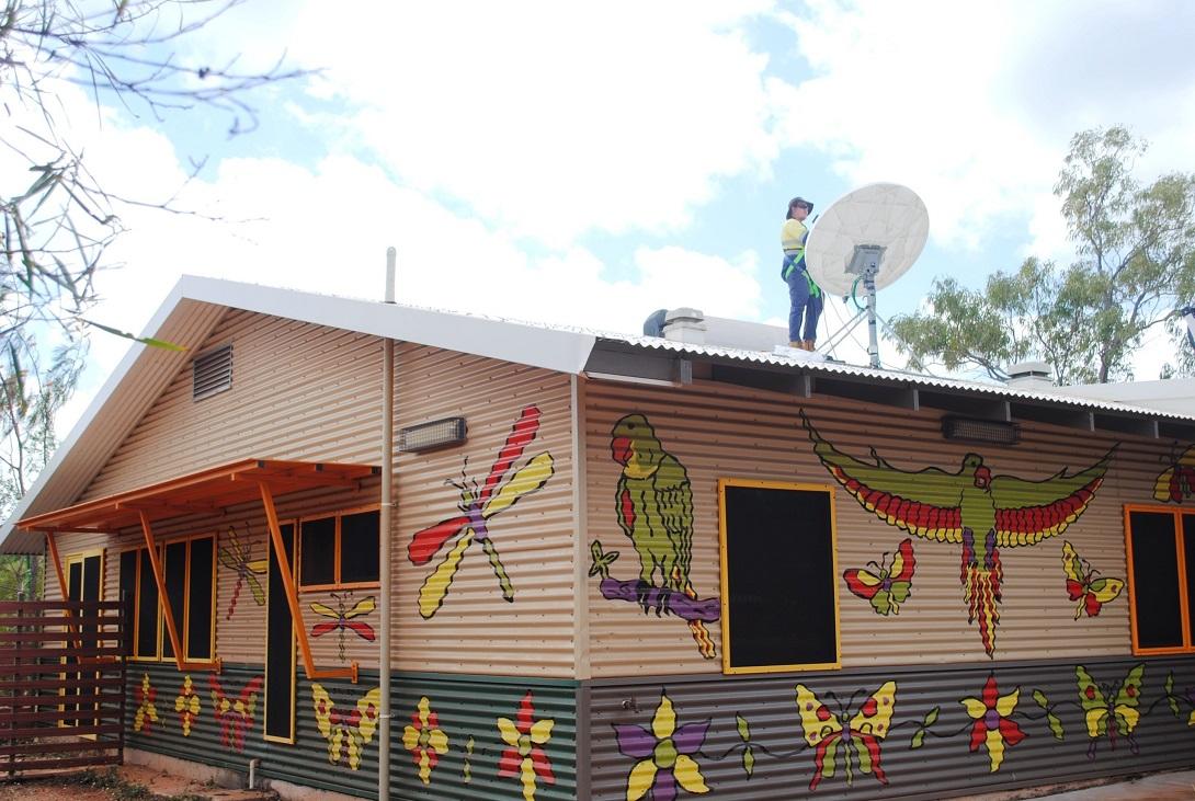 person on roof working on satellite dish