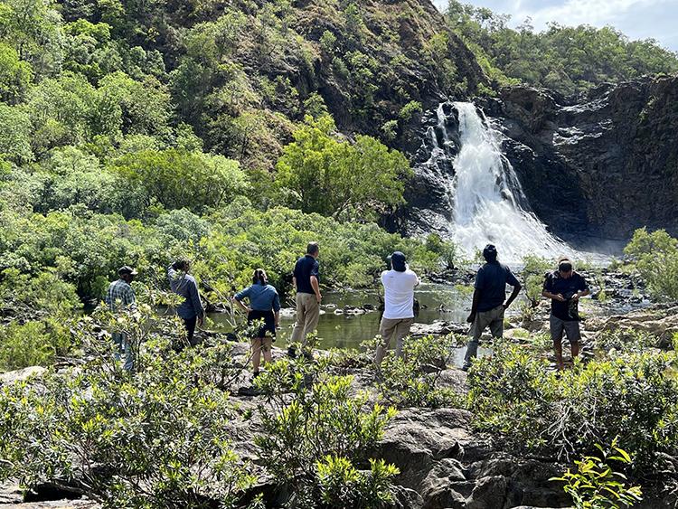 A group of people standing in front of a waterfall.