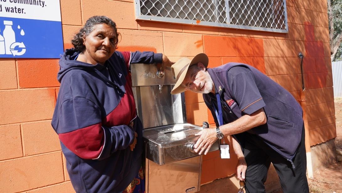 Two people smiling as they use one of the Water Refill Stations outside Council. Photo credit: MacDonnell Regional Council, NT